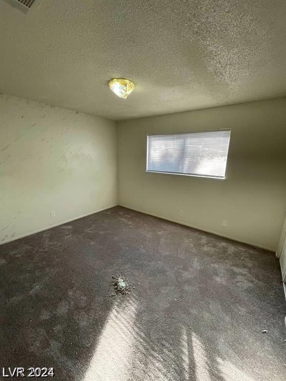 carpeted empty room with a textured ceiling