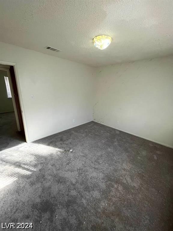 carpeted empty room with a textured ceiling