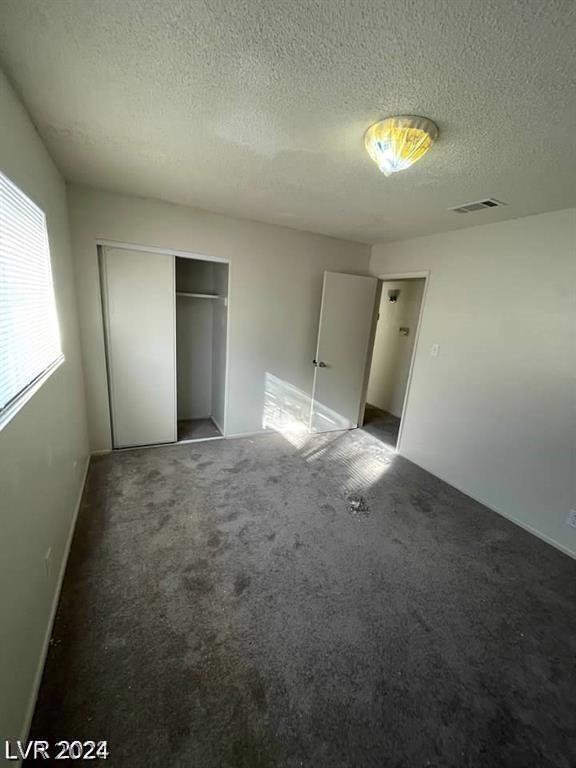 unfurnished bedroom featuring a closet, carpet, and a textured ceiling