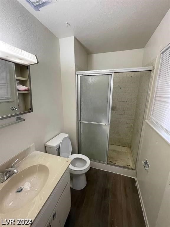 bathroom featuring walk in shower, a textured ceiling, toilet, vanity, and hardwood / wood-style flooring