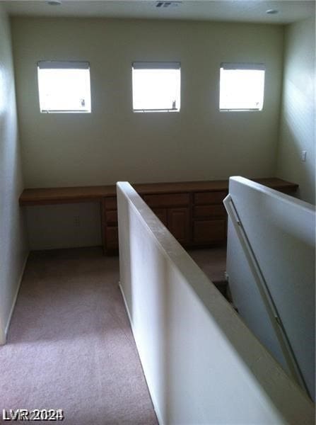 hallway featuring a healthy amount of sunlight and light colored carpet