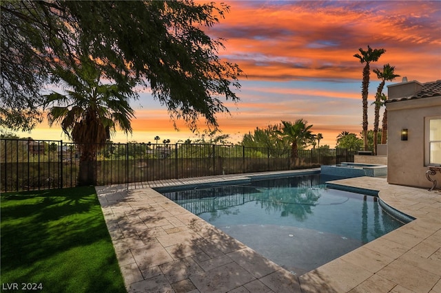 pool at dusk featuring a lawn and a patio area