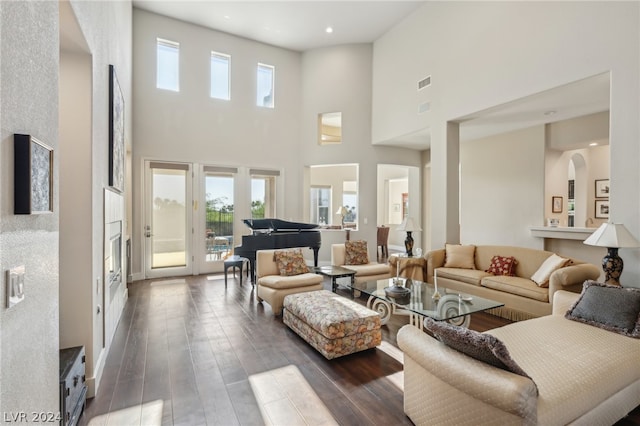 living room with a towering ceiling and dark hardwood / wood-style floors