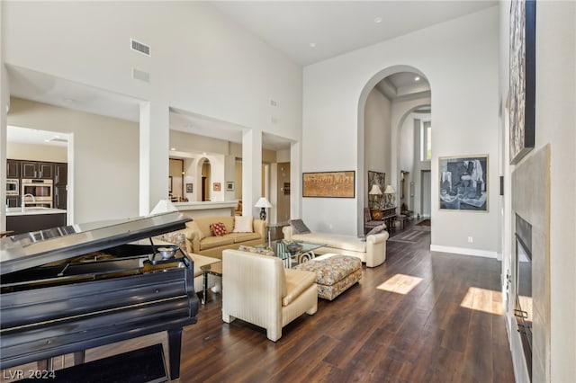 living room with a towering ceiling and dark hardwood / wood-style flooring