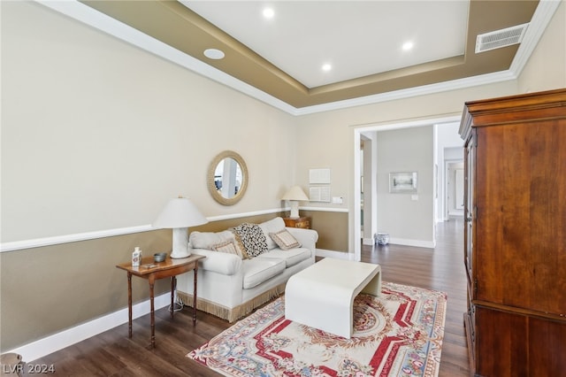 living room with ornamental molding, dark hardwood / wood-style flooring, and a tray ceiling