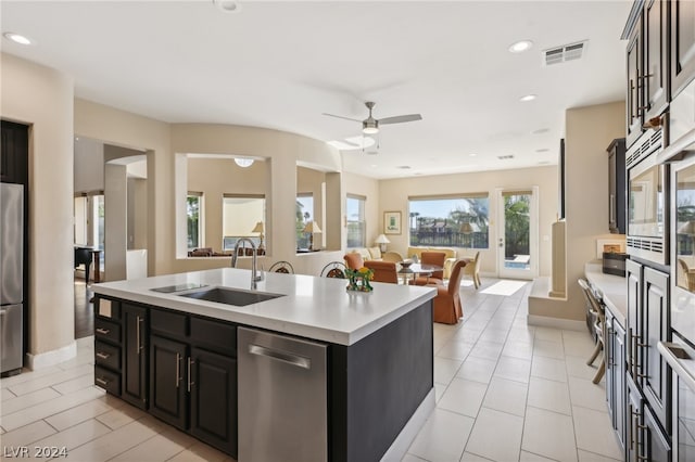 kitchen with stainless steel appliances, sink, light tile patterned floors, a kitchen island with sink, and ceiling fan