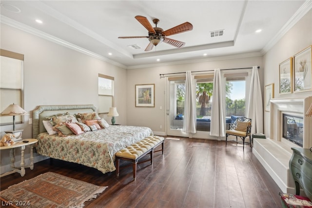 bedroom featuring ceiling fan, a tray ceiling, dark hardwood / wood-style flooring, and access to outside