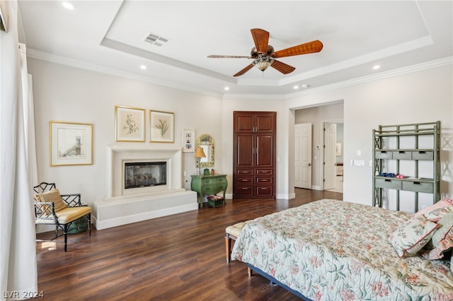 bedroom with a tray ceiling, crown molding, ceiling fan, and dark hardwood / wood-style floors