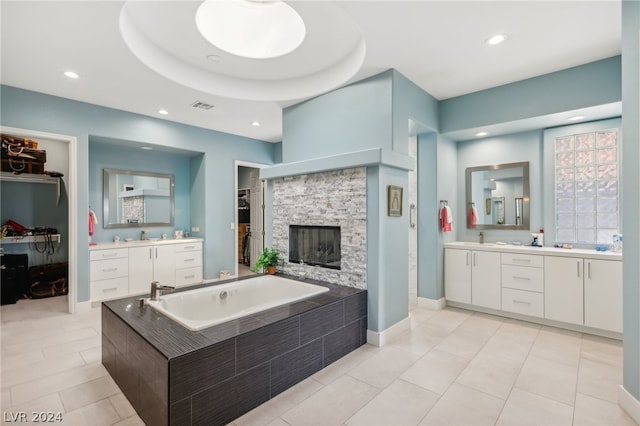 bathroom featuring a bathing tub, vanity, tile patterned floors, and a stone fireplace