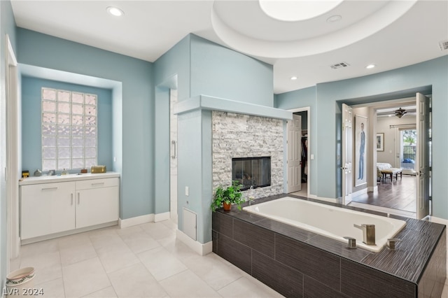 bathroom with vanity, tiled bath, tile patterned flooring, and a fireplace