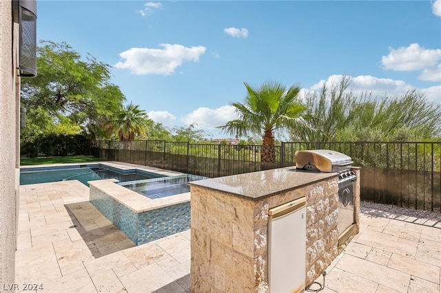 view of swimming pool featuring an outdoor kitchen, an in ground hot tub, and a patio area