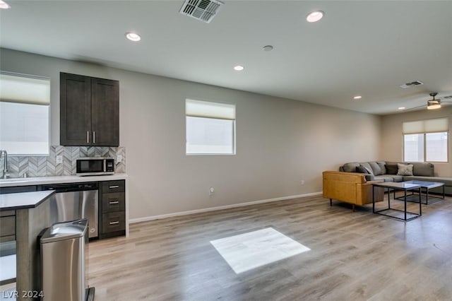 kitchen featuring sink, dark brown cabinets, appliances with stainless steel finishes, light hardwood / wood-style floors, and backsplash