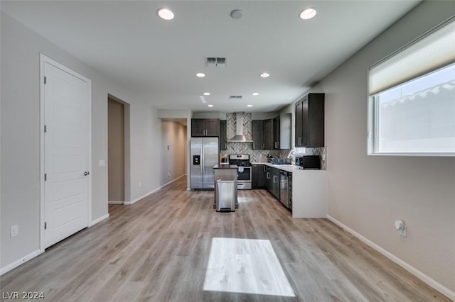 kitchen with a kitchen island, sink, backsplash, stainless steel appliances, and light wood-type flooring