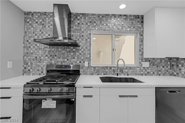 kitchen featuring black dishwasher, sink, white cabinets, stainless steel gas range oven, and wall chimney exhaust hood