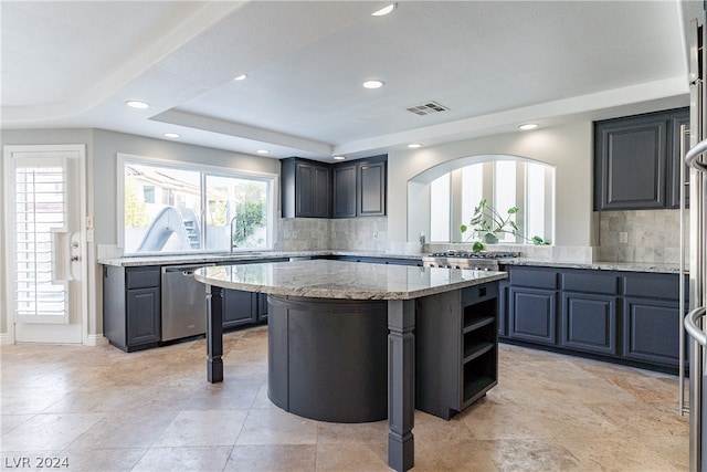 kitchen with dishwasher, tasteful backsplash, a kitchen island, and light stone countertops