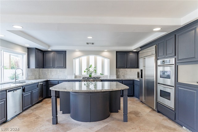 kitchen featuring a kitchen island, light stone countertops, backsplash, a kitchen bar, and stainless steel appliances