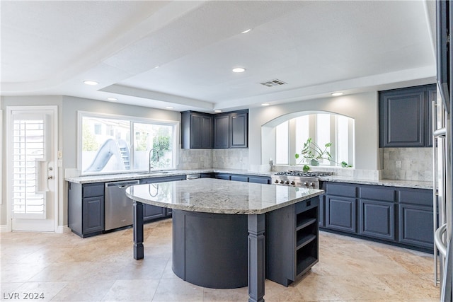 kitchen with dishwasher, a center island, light stone counters, sink, and tasteful backsplash