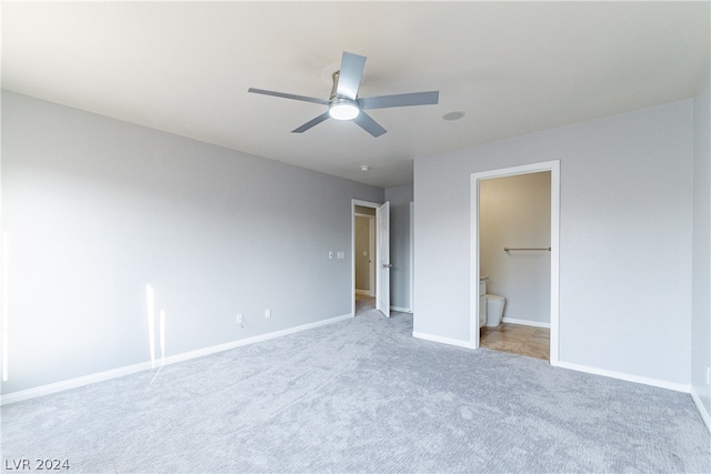 unfurnished bedroom featuring ensuite bath, light colored carpet, and ceiling fan