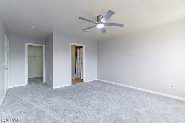 unfurnished bedroom with carpet flooring, ceiling fan, a walk in closet, and a closet