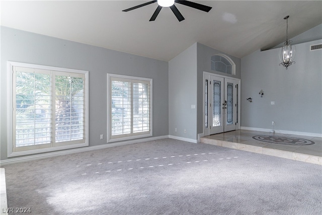 carpeted spare room featuring lofted ceiling and ceiling fan with notable chandelier