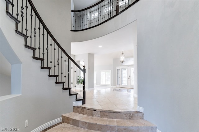 foyer entrance featuring tile patterned flooring, a high ceiling, and a notable chandelier