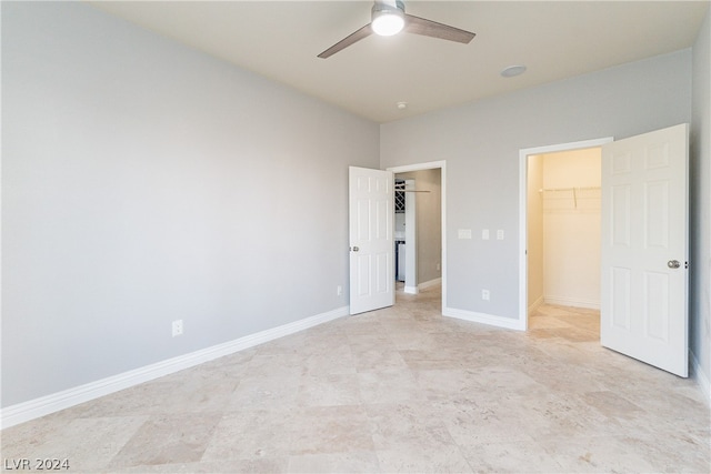 unfurnished bedroom with a closet, ceiling fan, and a spacious closet