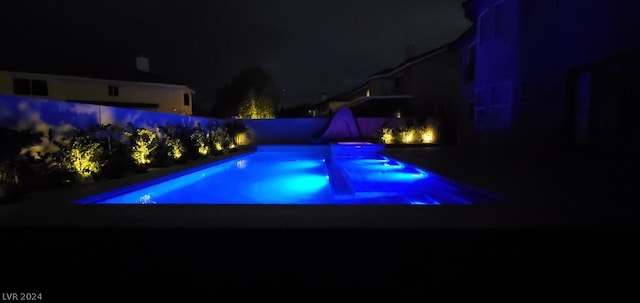 pool at twilight featuring a hot tub