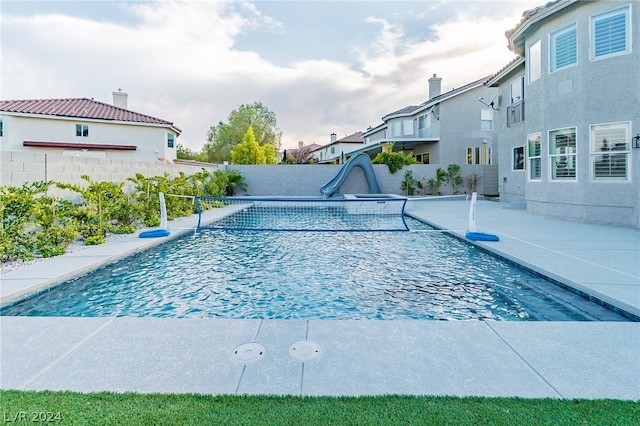 view of swimming pool with a water slide and a patio area