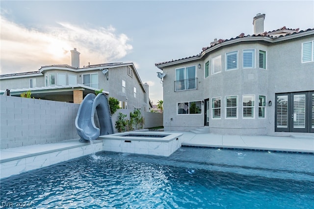 view of pool featuring a water slide, an in ground hot tub, and a patio area