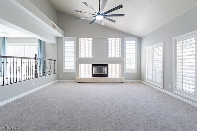 unfurnished living room with vaulted ceiling, ceiling fan, a fireplace, and a healthy amount of sunlight