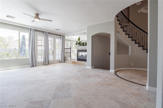 unfurnished living room with a multi sided fireplace and ceiling fan