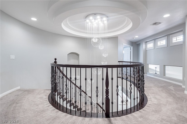 corridor featuring carpet flooring, a notable chandelier, and a tray ceiling