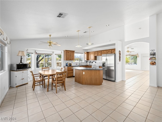 kitchen featuring light tile patterned floors, ceiling fan, appliances with stainless steel finishes, hanging light fixtures, and a center island