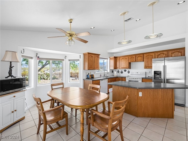 kitchen featuring light tile patterned floors, appliances with stainless steel finishes, a center island, and sink