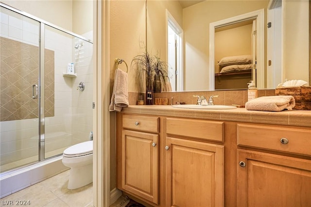 bathroom featuring walk in shower, vanity, toilet, and tile patterned flooring