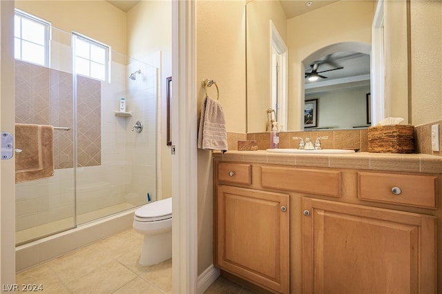 bathroom featuring tile patterned flooring, an enclosed shower, toilet, vanity, and ceiling fan