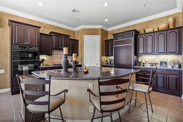 kitchen featuring dark brown cabinets, decorative backsplash, a center island, a breakfast bar area, and light tile patterned floors