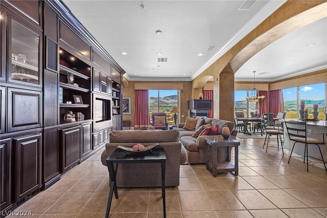 living room featuring a notable chandelier, built in shelves, light tile patterned floors, and ornamental molding