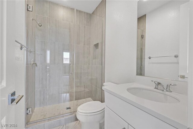 bathroom featuring vanity, a shower with door, and toilet