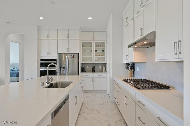 kitchen featuring sink, tasteful backsplash, light stone counters, appliances with stainless steel finishes, and white cabinets