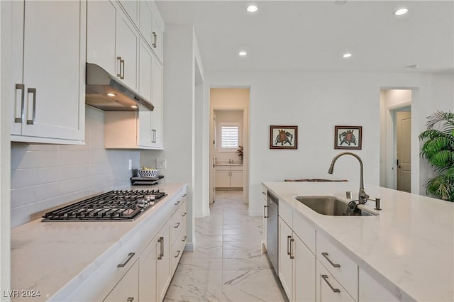 kitchen with sink, appliances with stainless steel finishes, white cabinetry, tasteful backsplash, and light stone countertops