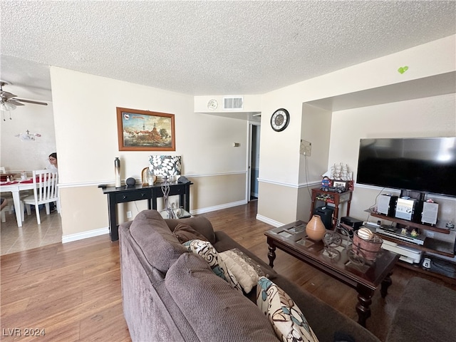 living room featuring ceiling fan, wood-type flooring, and a textured ceiling