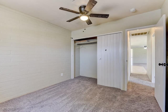 unfurnished bedroom with ceiling fan, brick wall, visible vents, a closet, and carpet