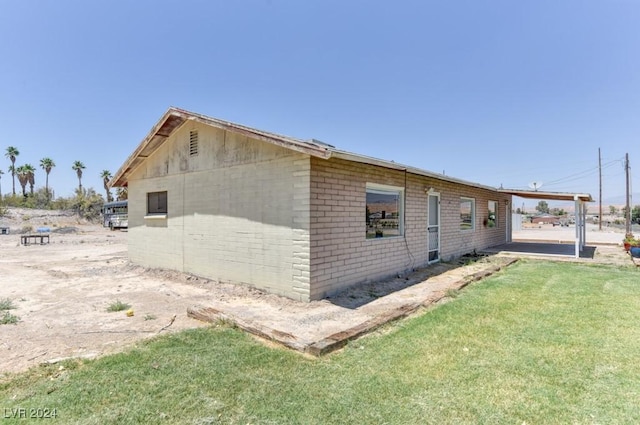 view of side of property with brick siding and a lawn