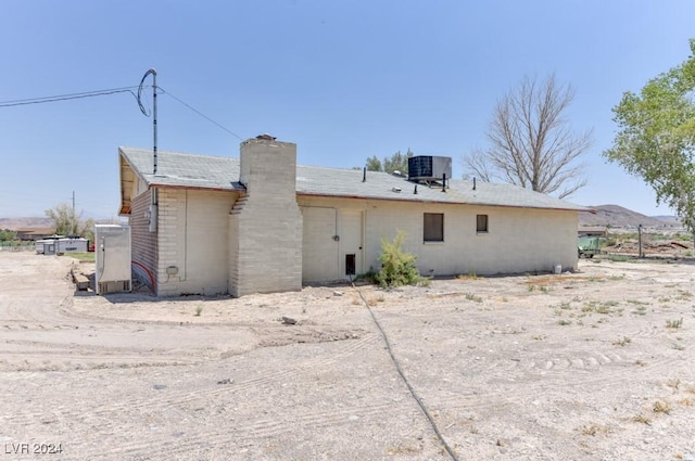 rear view of property with central AC and a chimney