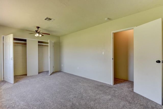 unfurnished bedroom featuring a ceiling fan, light colored carpet, visible vents, and two closets