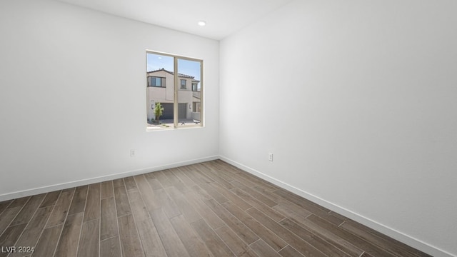 spare room with dark wood-type flooring, recessed lighting, and baseboards