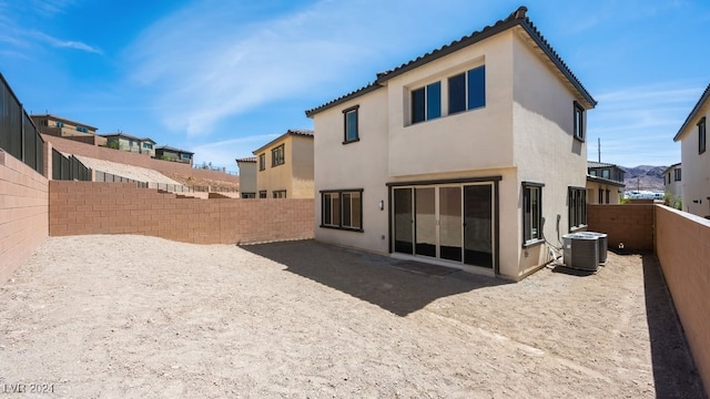rear view of property with central air condition unit, stucco siding, a fenced backyard, and a tiled roof