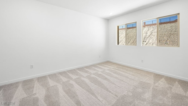unfurnished room with baseboards and light carpet