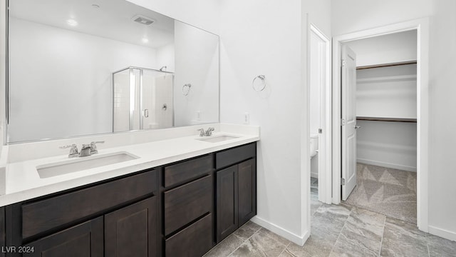 full bath featuring double vanity, baseboards, a stall shower, and a sink